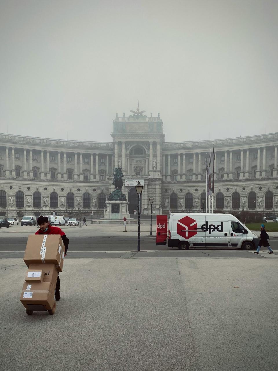 Repartidor de rojo descargando cajas en una plaza